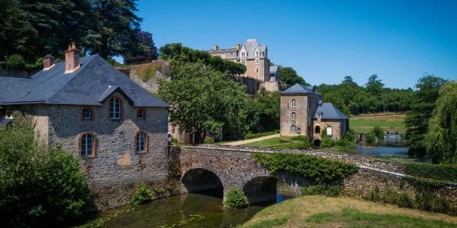 Vue du Moulin à eau de Thévalles. Au premier plan on voit une bâtisse et le pont en pierre enjambant le rivière l'Erve. En arrière plan, le château de Thévalles domine la vallée