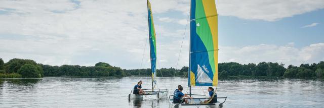 Deux catamarans naviguent sur le plan d'eau de La Rincerie