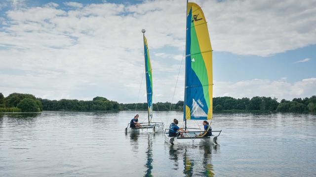 Deux catamarans naviguent sur le plan d'eau de La Rincerie