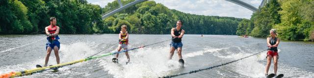 4 personnes font du ski nautique sur la Mayenne, tractées par le même bateau. En arrière plan on voit le nouveau viaduc de Château-Gontier