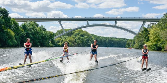 4 personnes font du ski nautique sur la Mayenne, tractées par le même bateau. En arrière plan on voit le nouveau viaduc de Château-Gontier