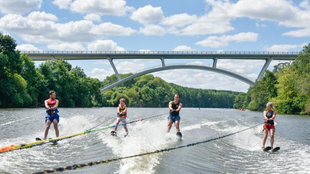 4 personnes font du ski nautique sur la Mayenne, tractées par le même bateau. En arrière plan on voit le nouveau viaduc de Château-Gontier