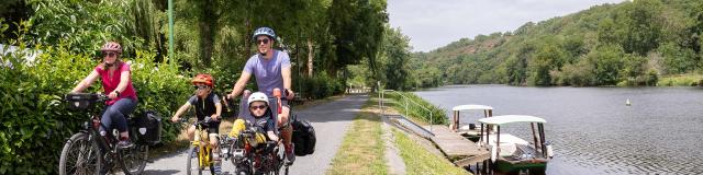 Une famille à vélo longe la rivière la Mayenne sur le chemin de halage