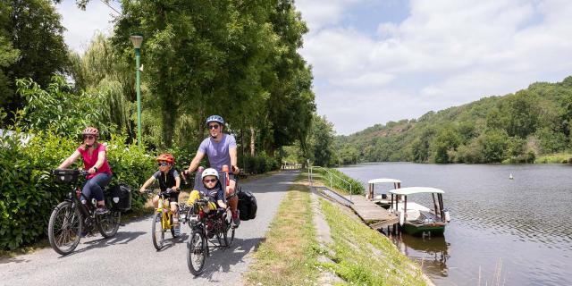 Une famille à vélo longe la rivière la Mayenne sur le chemin de halage