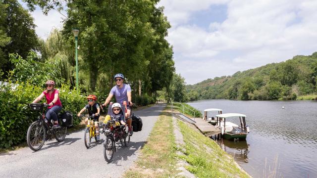 Une famille à vélo longe la rivière la Mayenne sur le chemin de halage