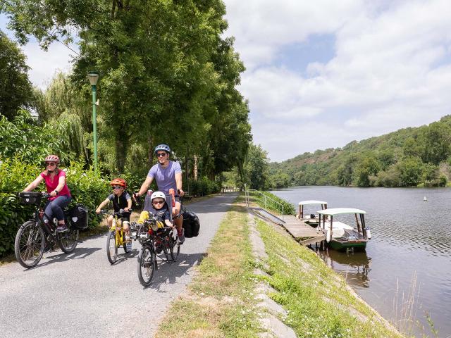 Une famille à vélo longe la rivière la Mayenne sur le chemin de halage