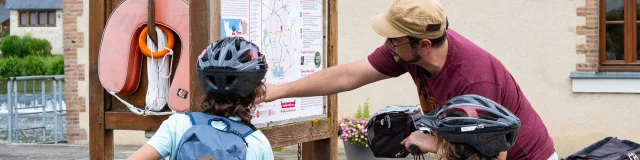 un papa et ses deux enfant regardent un panneau d'information en bord de Mayenne près d'une écluse