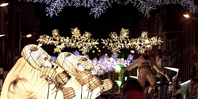 De grands ours lumineux déambulent dans les rues accompagnés des spectateurs.