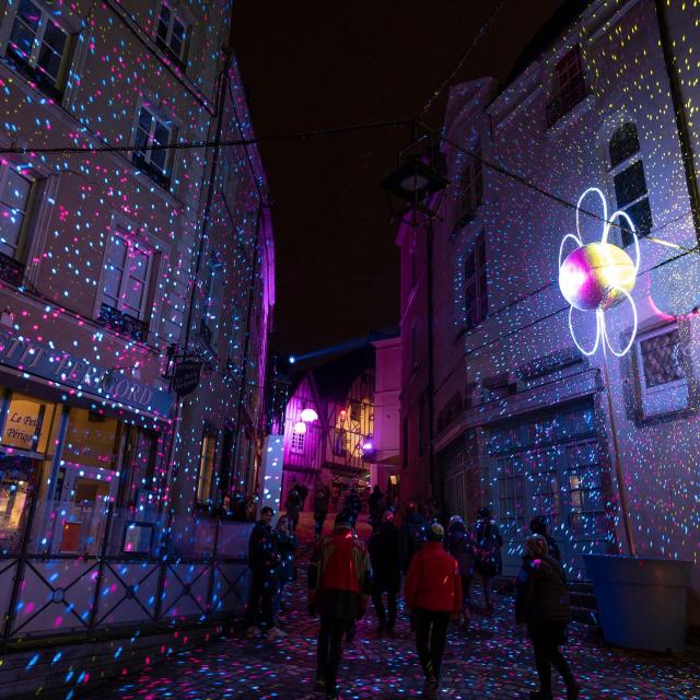 Rue du centre ancien lors des lumières de Laval. On y voit une fleur lumineuse et une multitude de points lumineux sur les maisons à colombage.