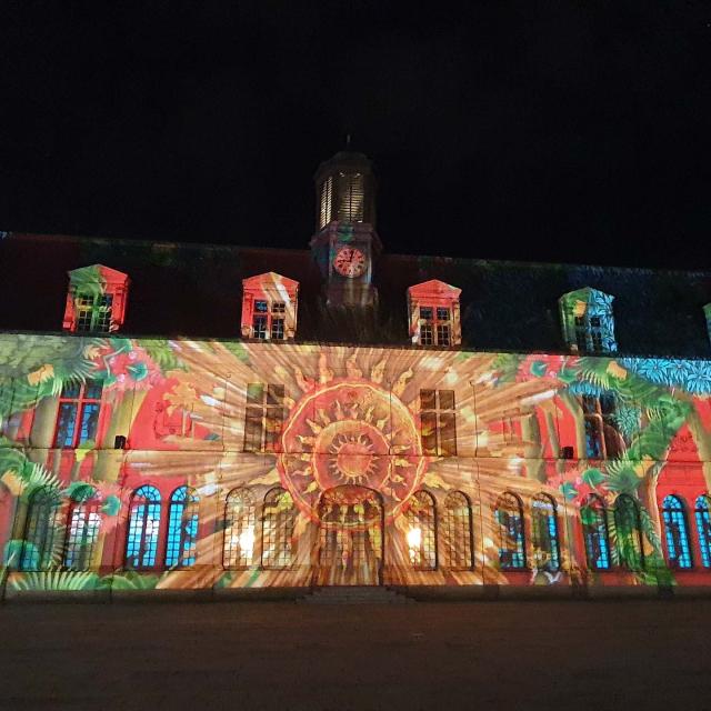 Projection sur la façade du château neuf de Laval. On y voit des motifs floraux très colorés et au centre ce qui semble être un grand soleil