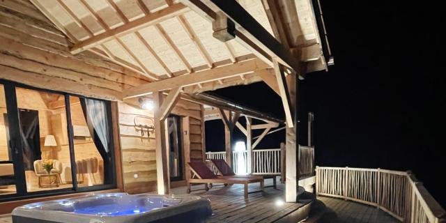 Dans la nuit, une cabane tout confort éclaire sa terrasse avec jacuzzi privatif