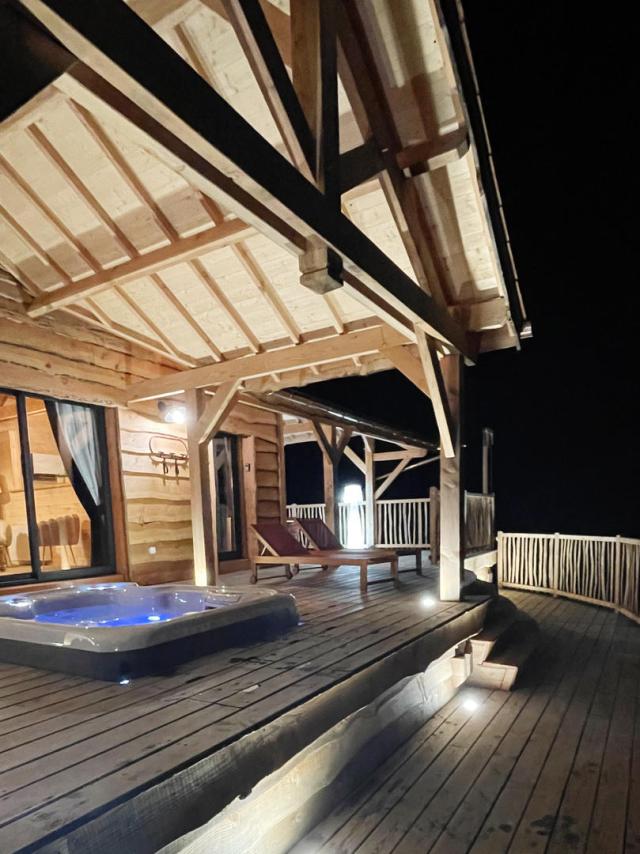 Dans la nuit, une cabane tout confort éclaire sa terrasse avec jacuzzi privatif