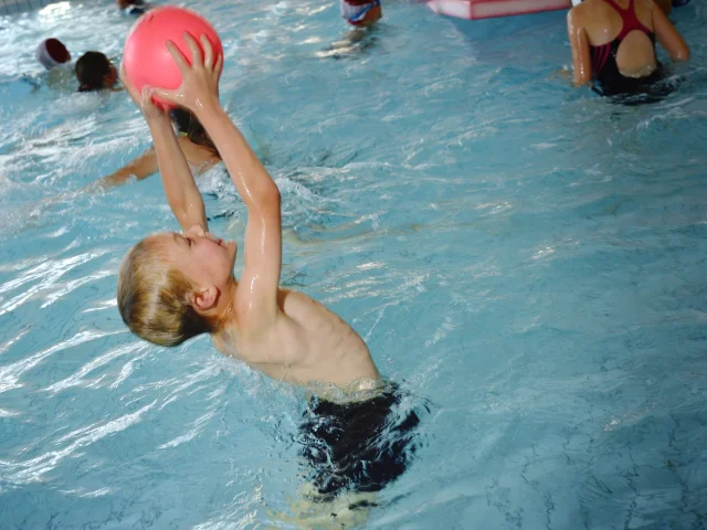 Un garçon joue au ballon dans la piscine