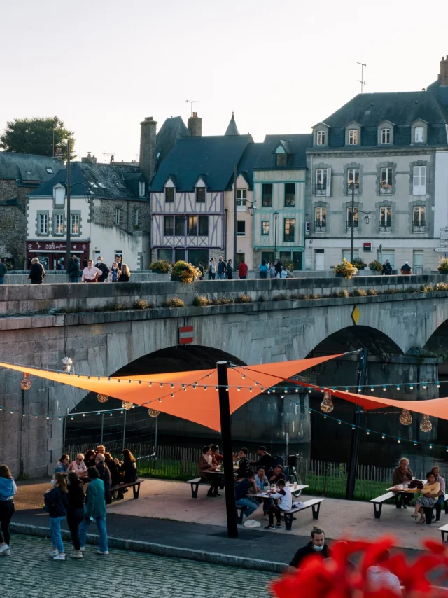 Dans une ambiance fetsive et colorée des personnes pique niquent en bord de rivière dans la ville de Mayenne