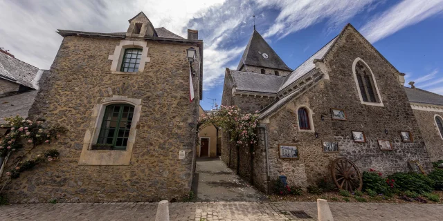 Vue de l'église de Saulges et d'une belle maison en pierre.