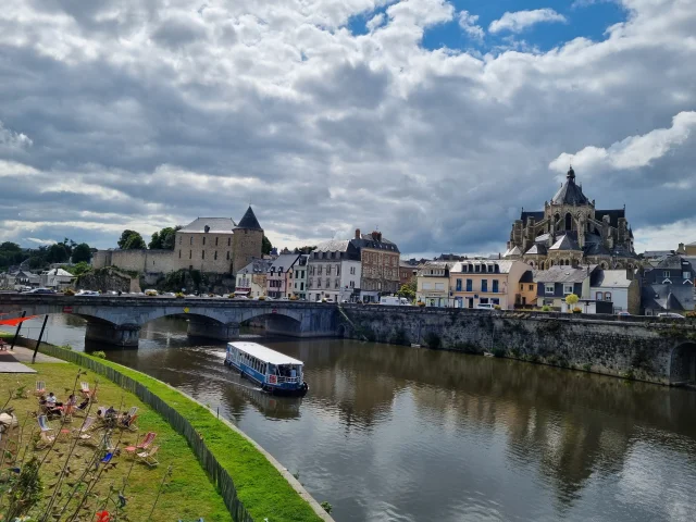 Le bateau La Meduana navigue sur le rivière La Mayenne à Mayenne en face du château et de la basilique