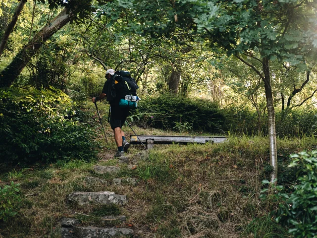 Un randonneur à Chailland marché dans un chemin creux au bord de l'eau