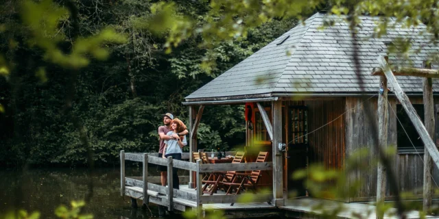 Un couple se tient sur la terrasse d'une cabane flottante