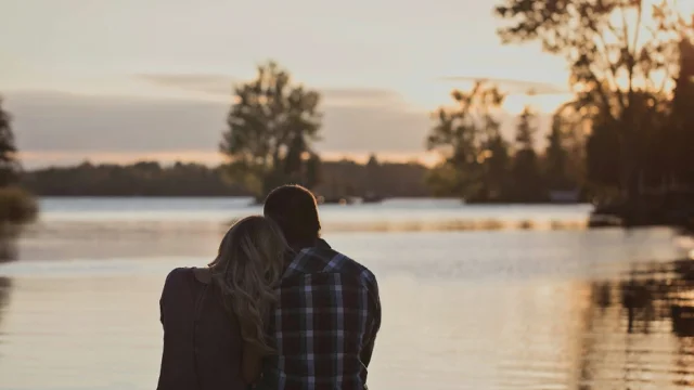 un couple au bord d'un lac regarde un coucher de soleil